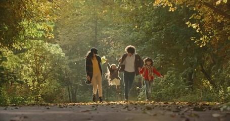 Young asian family of four walking down the road in golden autumn park, cheerfuly smiling - 4k - Powered by Adobe