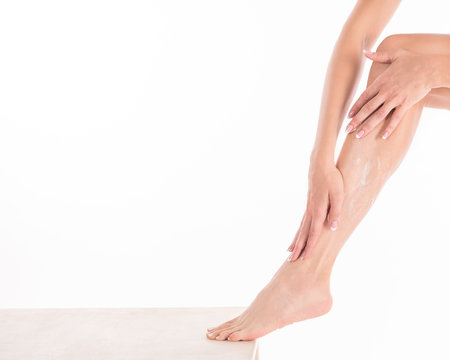 Female hands applying body cream on her leg, close up