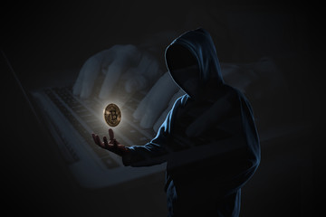 Golden Bitcoin floating above of hacker's hand in dark on hacker hacking with computer laptop...