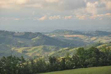 Hills and fields with loose buildings during sunset in northern Tuscany, Italy.