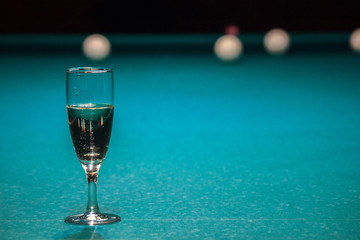 a glass of champagne is on the pool table. the winner of the game, the champion drinks a glass of sparkling wine. Hobbies, sports, passionate people.