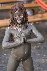 close portrait of a girl in a swimsuit in a mud mask on the whole body
