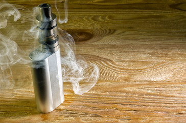 Electronic cigarette standing on the table shrouded in steam