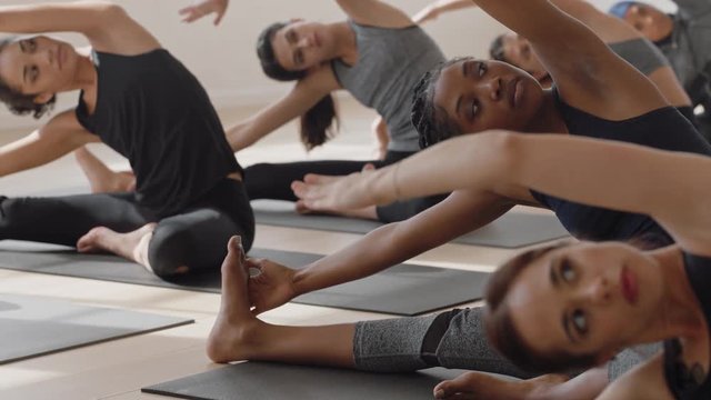 healthy yoga woman practicing seated side bend pose young african american female enjoying fitness lifestyle exercising in studio with group of multiracial women