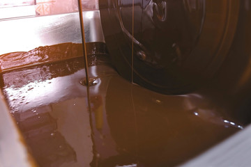 Warm liquid chocolate in Chocolate tempering machine. Close-up view. Production of chocolate candys.