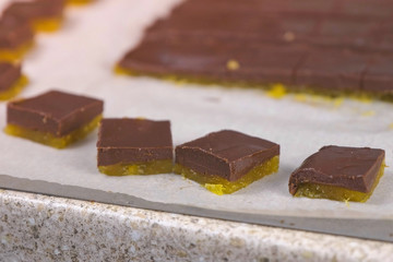 Cutting filling for chocolate candies praline with apricot marmalade on baking paper.