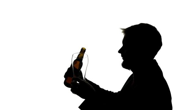 Man pours beer into a glass goblet and drinks . Side view. Silhouette White background