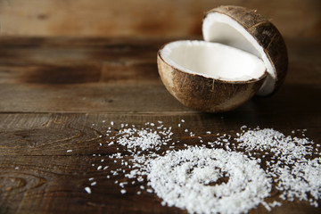 coconut halves with coconut flakes on a wooden background for beauty and spa with copy space for text