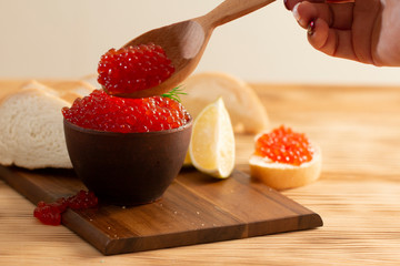 red caviar in a ceramic dish on a wooden background in a rustic style with space for text