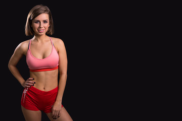 Slim athletic girl smiling at you on a black background