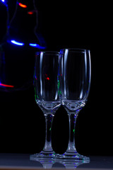 empty wine glass close-up on a black background with a place for text on the background of Christmas lights