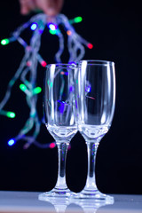 empty wine glass close-up on a black background with a place for text on the background of Christmas lights