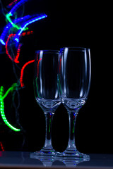 empty wine glass close-up on a black background with a place for text on the background of Christmas lights