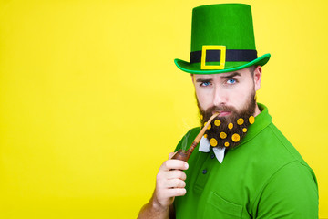 Happy young adult man male in green shirt, green leprechaun hat and tie bow with gold coins in...