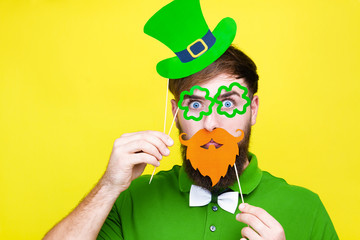 Happy young adult man male in green shirt, green leprechaun hat and tie bow with glasses lucky...