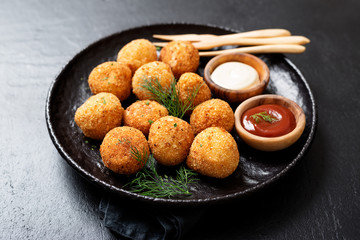 Potato croquettes - mashed potatoes balls breaded and deep fried, served with different sauce.