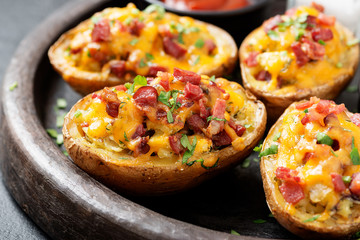 Hot baked potato topped with bacon, green onions and cheddar cheese. - obrazy, fototapety, plakaty
