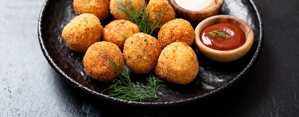 Potato croquettes - mashed potatoes balls breaded and deep fried, served with different sauce.