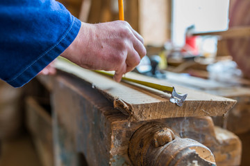 Carpenter measuring a long oak board, focus on the  hand , shallow depth of field.