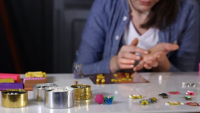 Woman creating hand made jewelry from polymer clay in her studio.