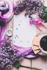Morning cup of tee, cookies, and lilac flower on wooden table from above. Beautiful breakfast. Flat lay style with copy space