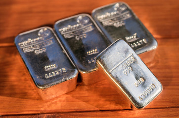 Four cast silver bullion on a mahogany background. Selective focus.