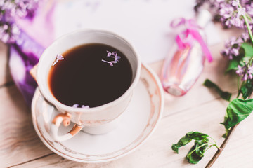 Morning cup of tee, cookies, and lilac flower on wooden table from above. Beautiful breakfast. Flat lay style with copy space