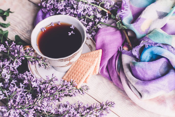 Morning cup of tee, cookies, and lilac flower on wooden table from above. Beautiful breakfast. Flat lay style with copy space