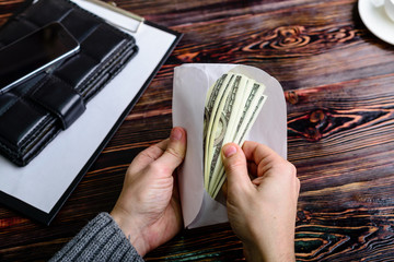 Man counting money, US dollars, in envelope just given by his partner - bribery and corruption...