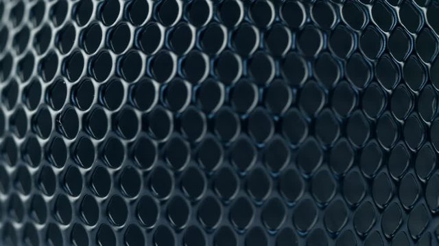 Black metal grid rotating on dark background. Close up macro 4k footage.