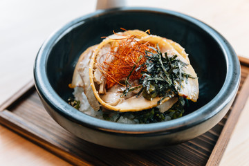 Japanese Chashu Don: Steam Rice topping with Roasted Pork Belly, Yolk, Dried Seaweed and Saffron. Served in black ceramic bowl with Shoyu sauce.