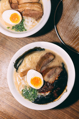 Top view of Ramen Pork Bone Soup (Tonkotsu Ramen) with Chashu Pork, Scallion, Sprout, Onion, Menma and Dried Seaweed and boiled egg served with fresh garlic.