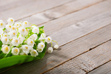 bouquet of lily of the valley on old weathered wooden table background
