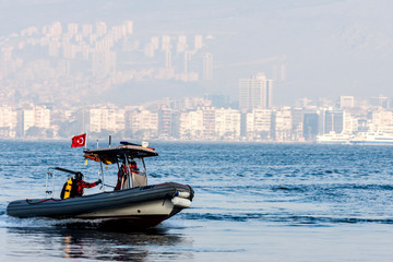 Policemen divers on a rubber dinghy going fast on the seawater in front of Izmir (Turkey) -...