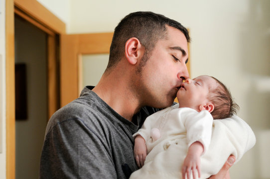 Father kissing his newborn baby girl.