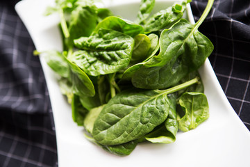 Spinach on white plate on table. Healthy food concept