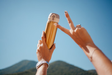 gold tumbler mug in woman's hands. mountain on background
