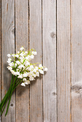 bouquet of lily of the valley flowers on old weathered wooden table background