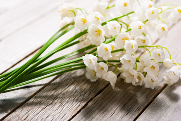 bouquet of lily of the valley flowers on old weathered wooden table background