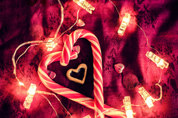 The heart of lollipops among the garlands on a dark background.