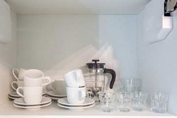 tea set and kettle on the shelf in the kitchen cupboard