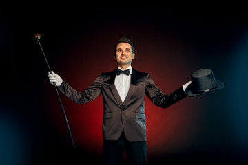 Professional Occupation. Showman in suit standing isolated on wall with hat and cane starting show...