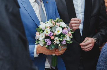 Groom in blue suit is holding beautiful elegant wedding bouquet in hands. Eustoma, freesia and pink roses flowers.