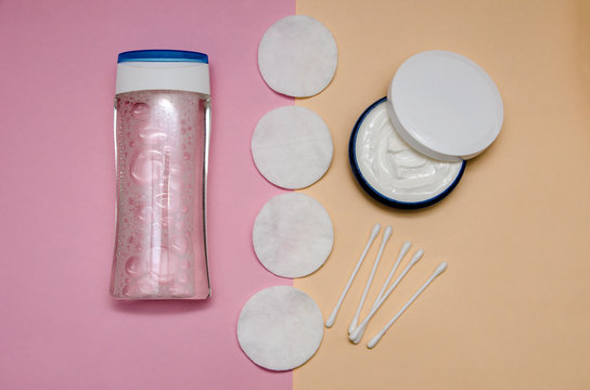 lotion, cotton swabs, cotton disks and cream in a jar. Products for body care and personal care on a pink pastel background. View from above. The trend of minimalism. Flat lay