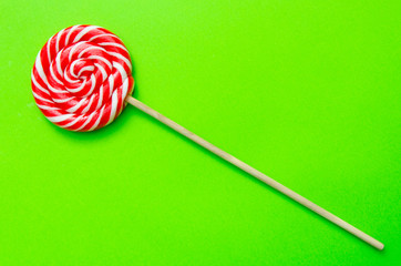 lollipop, a beautiful red and white striped round lollipop on a green background