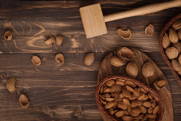 Flat lay of almonds in the wicker plates with other accessories on brown wooden background top view 9