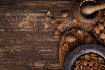 Obraz na płótnie Canvas Flat lay of almonds in black plate with other accessories on brown wooden background top view