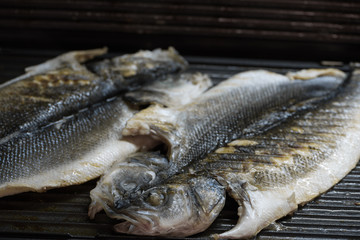 Raw seabass fish on electric grill spread in half