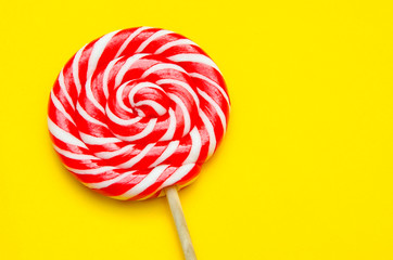 lollipop, a beautiful red and white striped round lollipop on a yellow background