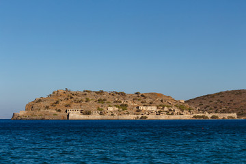 Fototapeta na wymiar View over the island of Spinalonga, Crete, Greece. Ruins of ancient Venetian medieval fortress. It was the last leper colony in Europe. People with the Hansen's disease lived here.